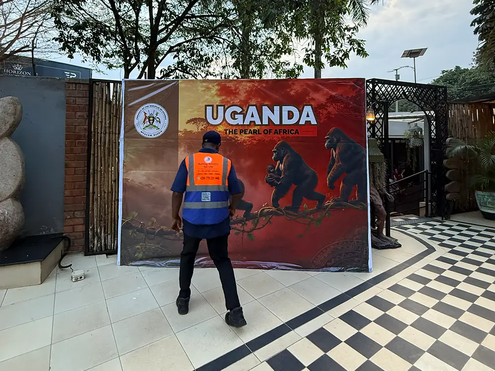 Kamog Artistry team member checking backdrop alignment, tension and presentation during event setup in Kololo
