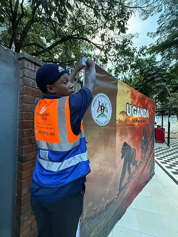 Kamog Artistry installer mounting the printed tourism artwork onto the reusable backdrop frame