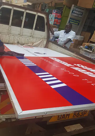 Completed Goodwill and Crown Crane framed PVC hardware sign being loaded onto a pickup for delivery