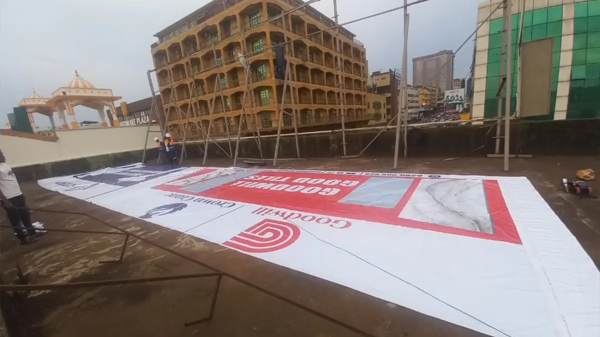 The extra-large printed face laid out across the rooftop before lifting