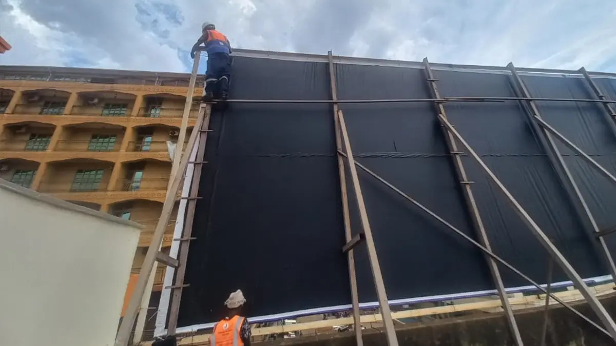 Upper edge of the Goodwill rooftop billboard being aligned and tensioned