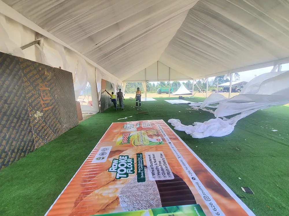 Raw Tooke Flour backdrop before installation — A 6m × 2.5m PVC banner laid out before installation inside the VIP tent area.